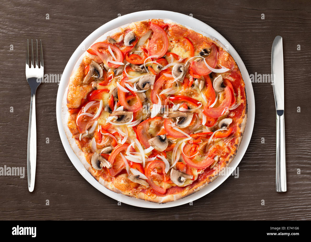 Pizza italiana vista dall'alto sulla piastra con la forchetta e coltello Foto Stock