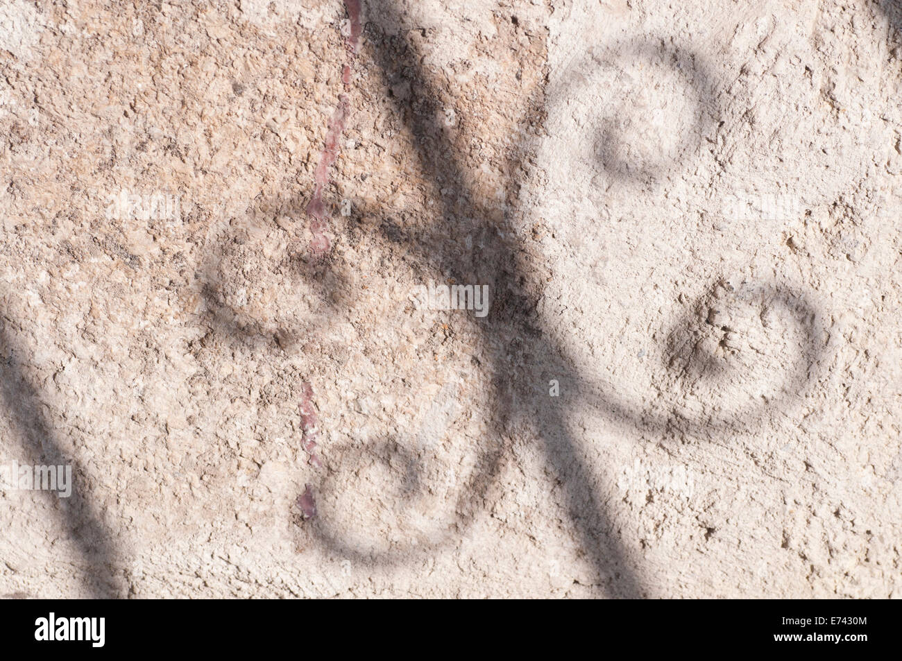 Un ombra da una scalinata in ferro battuto contro il grigio di un muro intonacato Foto Stock