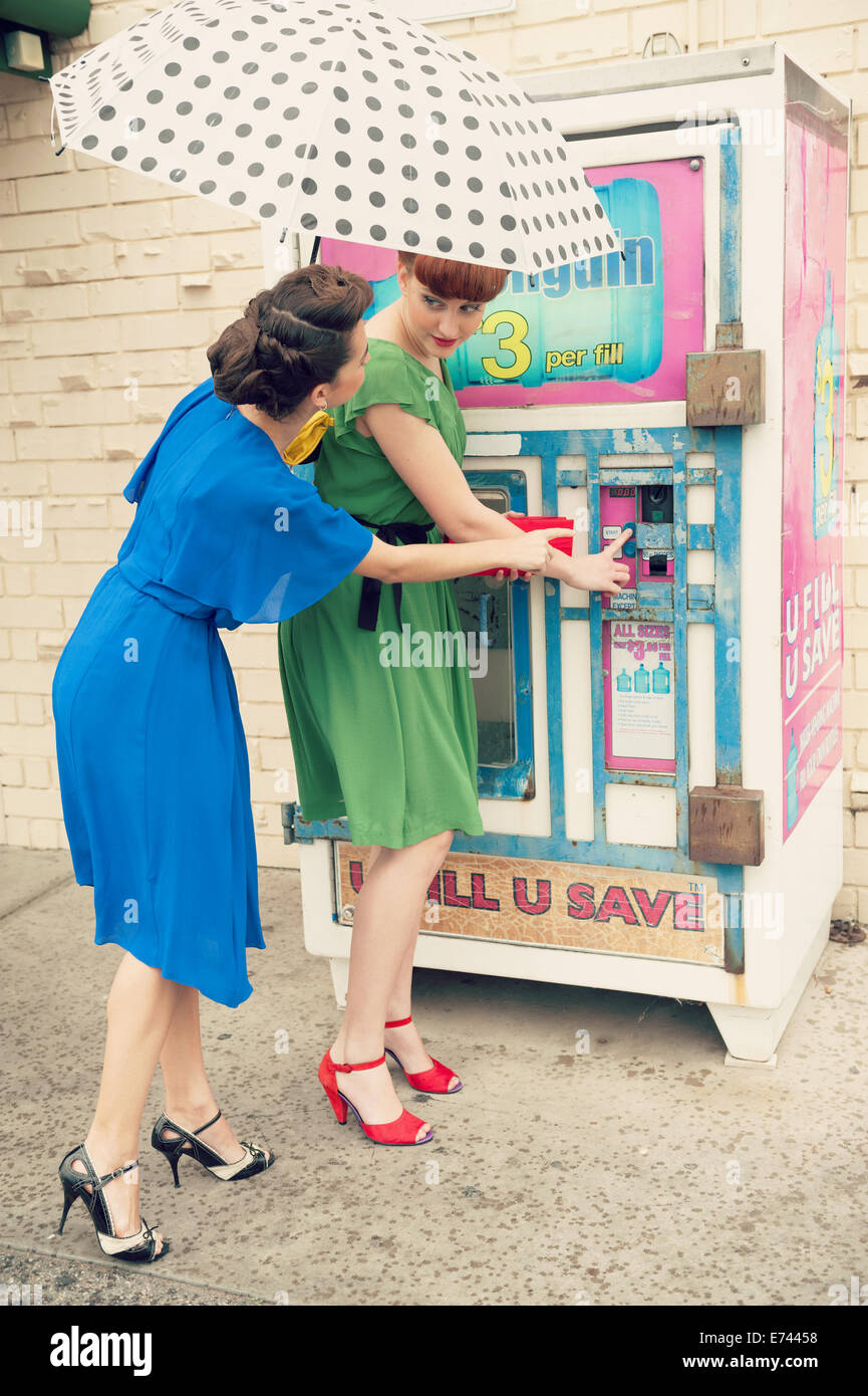 Due belle ragazze in stile retrò vicino a una macchina di acqua Foto Stock