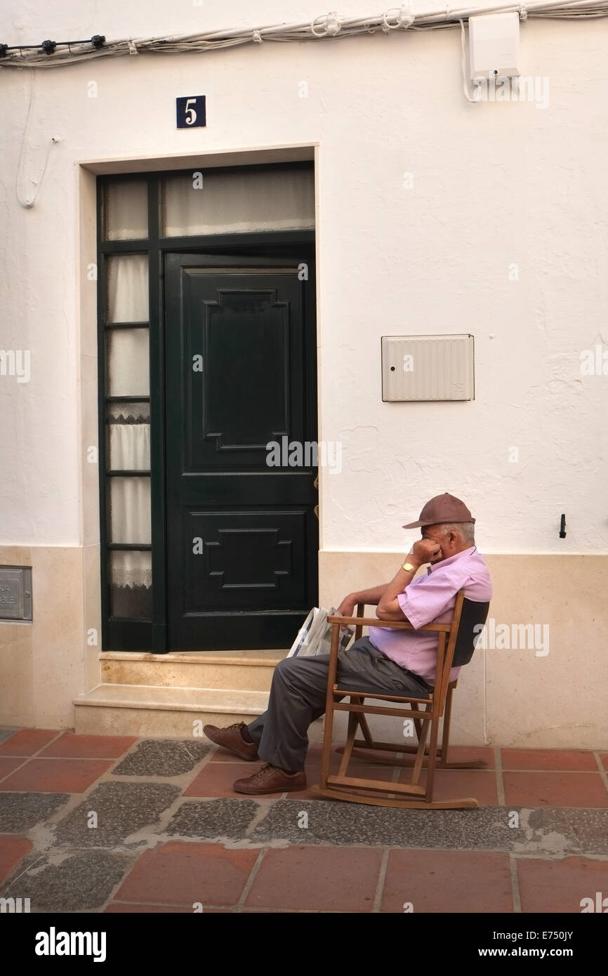 Il vecchio uomo snoozes al di fuori di casa sua a Mercadal, Menorca, Spagna Foto Stock