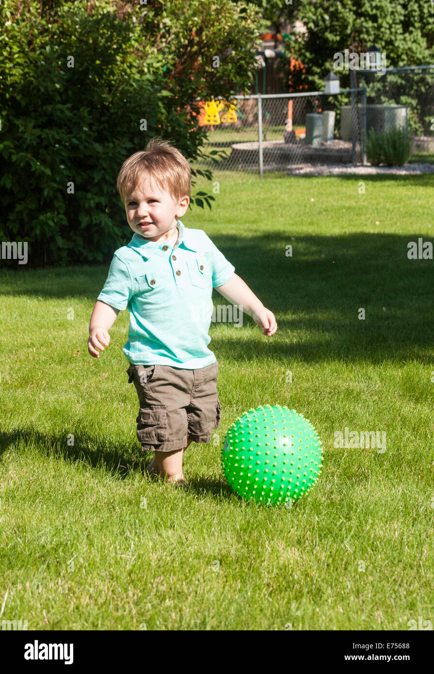 Riproduzione toddler verde con sfera di plastica nel cortile, STATI UNITI D'AMERICA Foto Stock