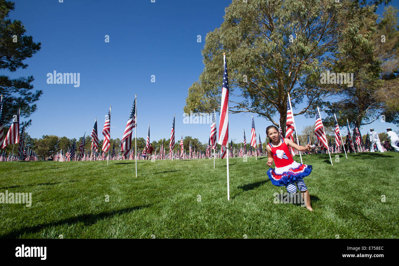 I bambini in esecuzione attraverso un campo di bandierine americane in libertà nel Parco Ridgecrest, California. Foto Stock