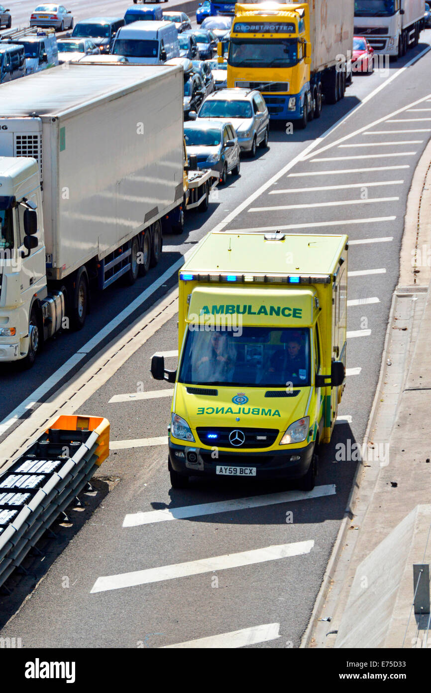 Ambulanza di emergenza tramite autostrada spalla duro per raggiungere la localizzazione degli incidenti in corrispondenza della parte anteriore del paralizzata traffico autostradale Foto Stock