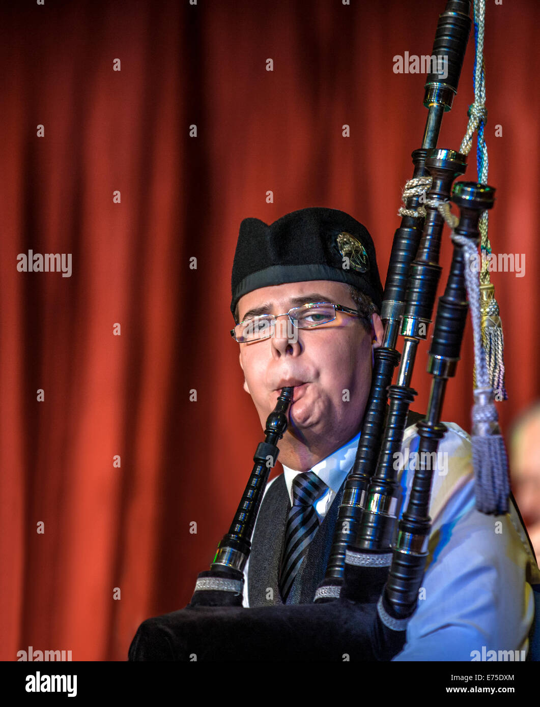 Scottish musicien bagpiper1 da una banda agisce come host all'arrivo dei transatlantici nel porto di Invergordon in Scozia Foto Stock
