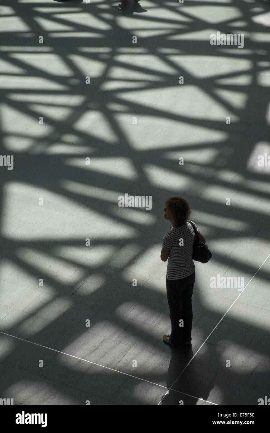 Le ombre proiettate sul pavimento sulla luminosa giornata di sole in London Kings Cross Station Foto Stock