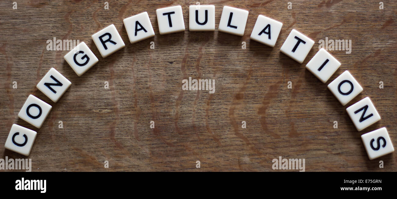 Congratulazioni scritto in piastrelle su una superficie di legno Foto Stock