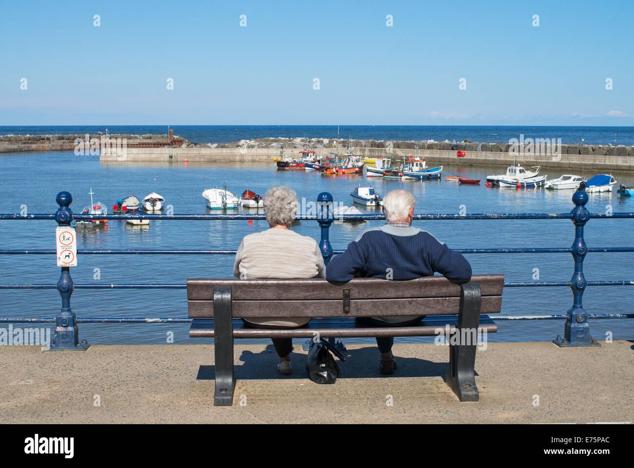 Coppia senior seduto a guardare fuori per il Mare del Nord, Staithes North Yorkshire, Inghilterra, Regno Unito Foto Stock