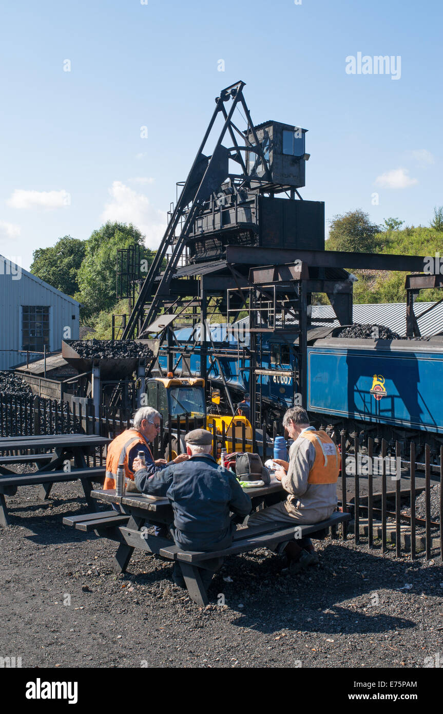 Lavoratori NYMR avente il pranzo a Grosmont loco capannoni con vapore loco in background, North Yorkshire, Inghilterra, Regno Unito Foto Stock