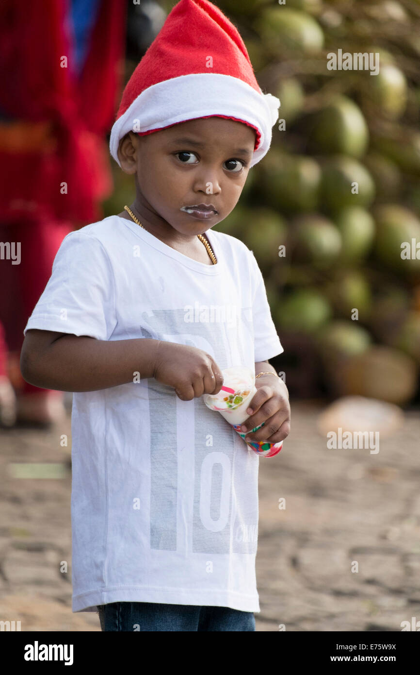 Ragazzo di mangiare il gelato, che indossa un Berretto di Babbo Natale, o di Kochi Cochin, Kerala, India Foto Stock