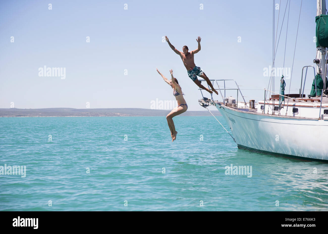Giovane salta fuori da barca in acqua Foto Stock