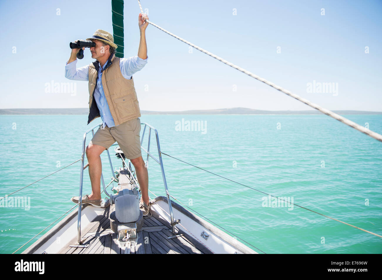 Uomo anziano guardando fuori il binocolo sul bordo della barca Foto Stock