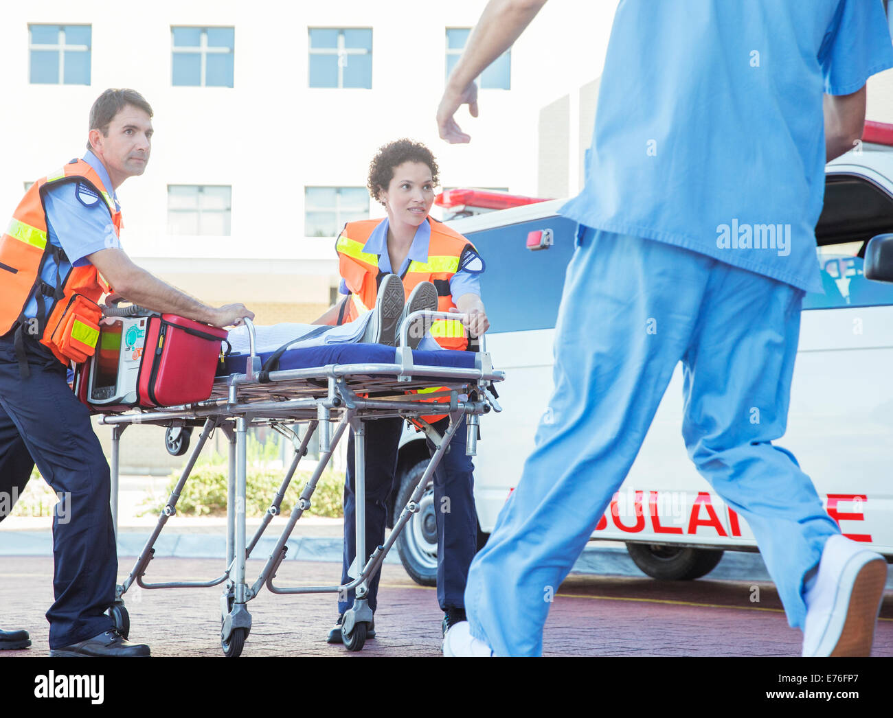 I paramedici wheeling paziente in ospedale parcheggio Foto Stock
