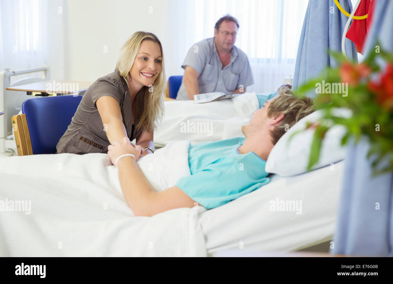 Donna che mantiene il fidanzato mano nella stanza di ospedale Foto Stock