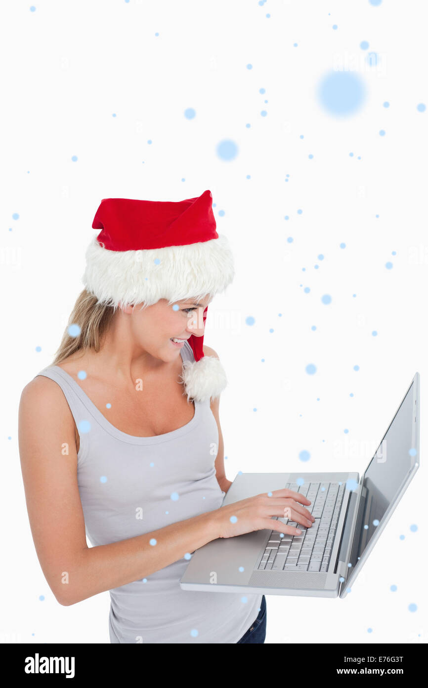 Immagine composita della donna con un cappello di Natale usando un computer portatile Foto Stock