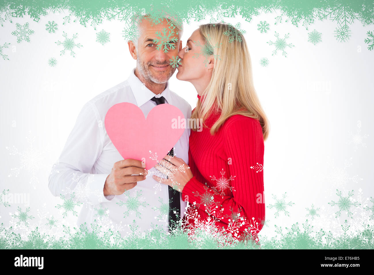 Immagine composita di uomo bello azienda cuore di carta ottenendo un bacio dalla moglie Foto Stock