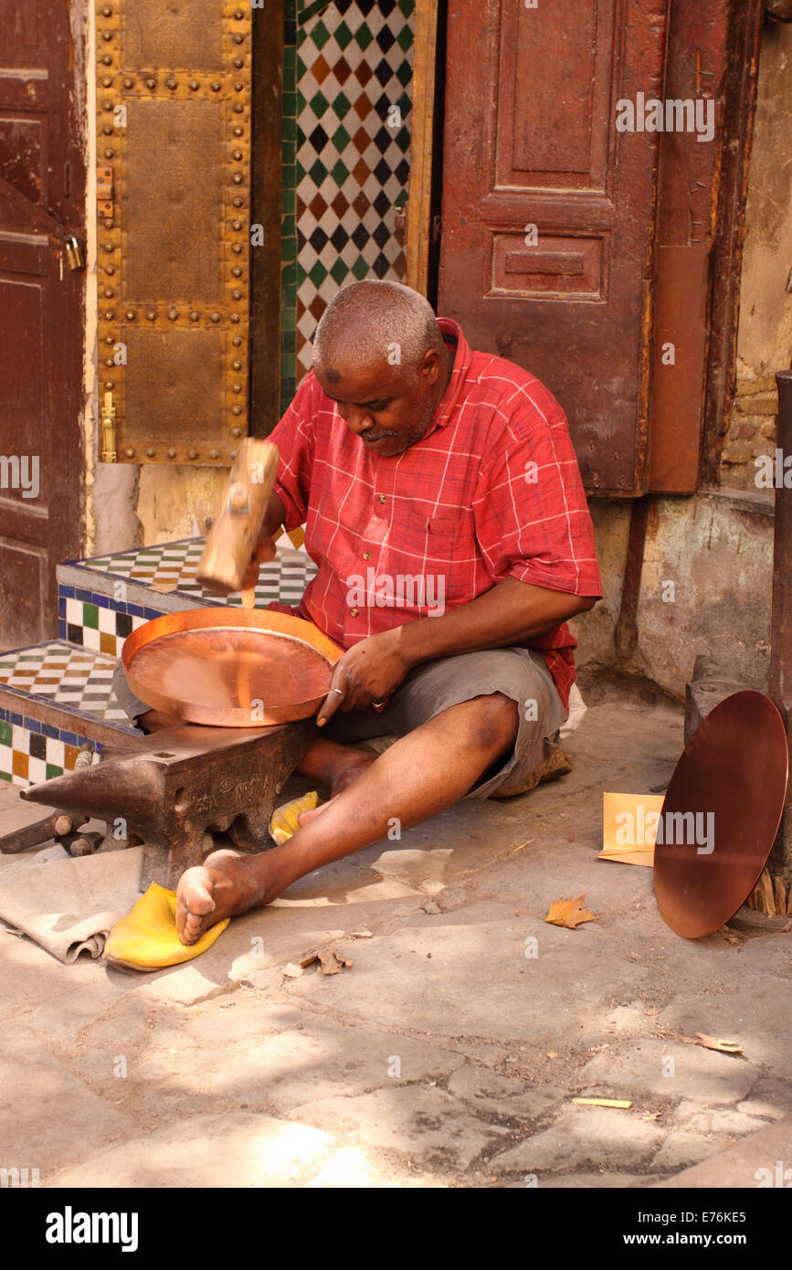 Fes Marocco un artigiano locale nel luogo Seffarine area della Medina rendendo un vassoio di rame battendo con un mazzuolo di legno Foto Stock