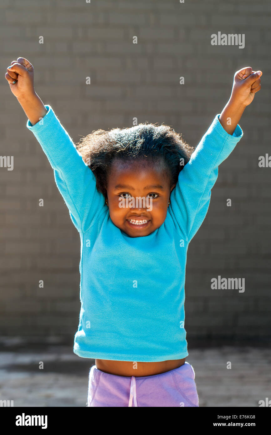 Ritratto di poco ragazza africana i bracci di sollevamento all'esterno. Foto Stock