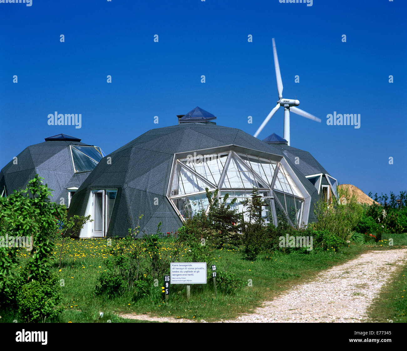 Case in forma di cupole geodetiche in Dyssekilde eco-villaggio, Danimarca. Turbina eolica in background. Foto Stock