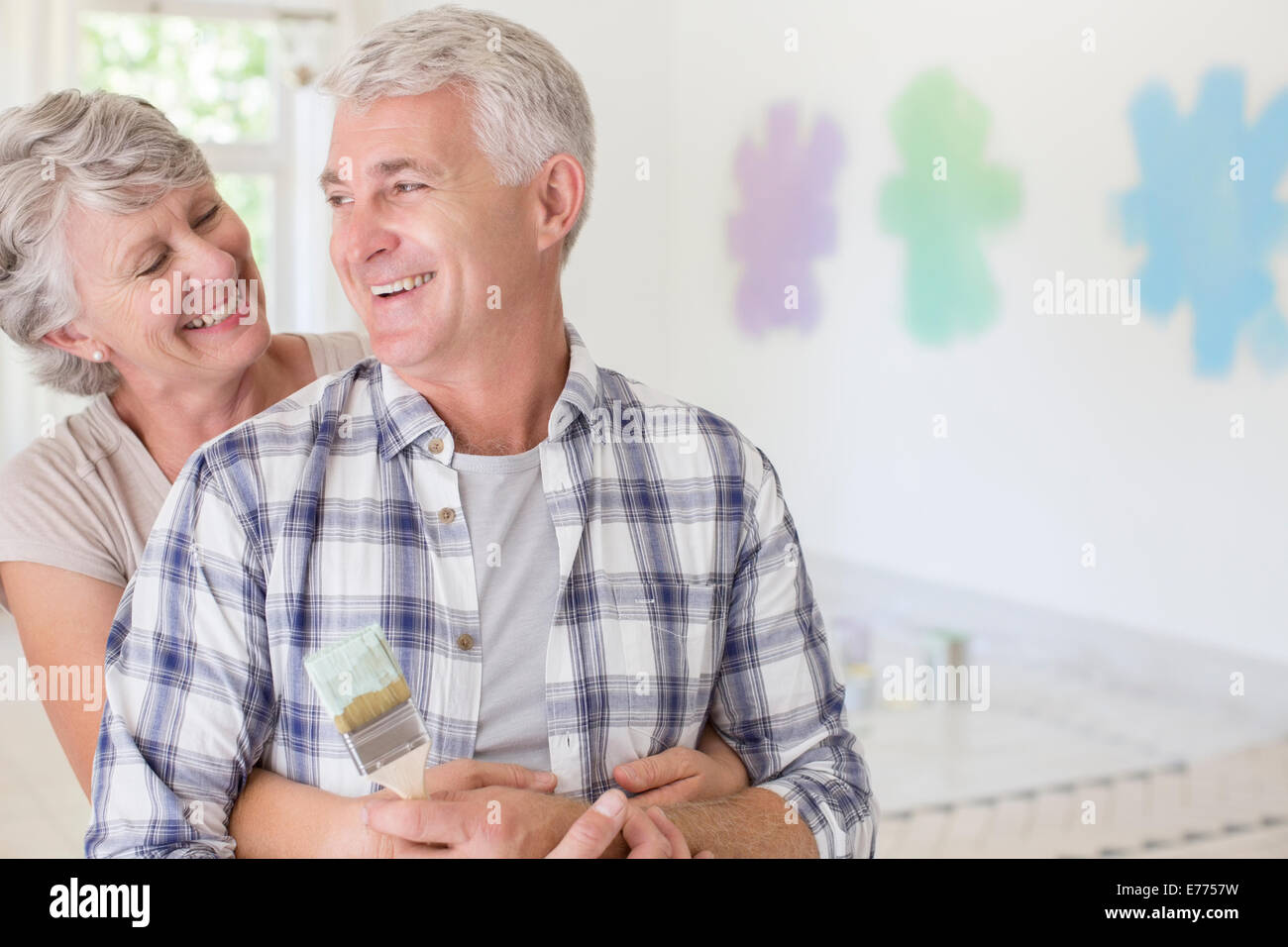 Coppia di anziani abbracciando con pennello in spazio abitativo Foto Stock