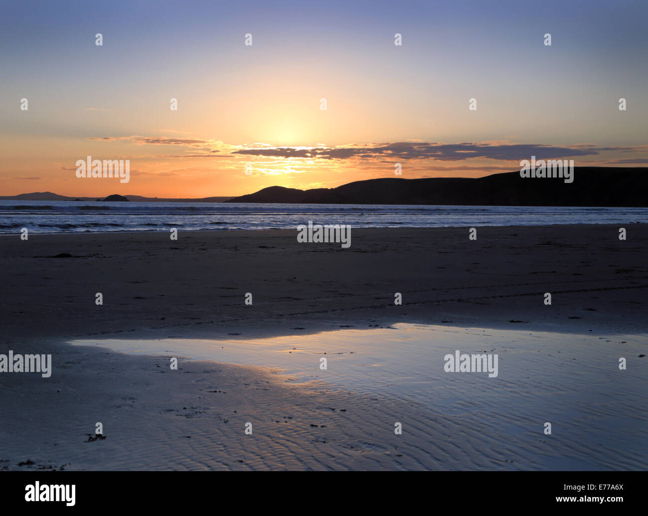 Newgale spiaggia di Pembrokeshire al tramonto con il sole che tramonta, riflette luce splendida, liscio espansiva di sabbie Foto Stock