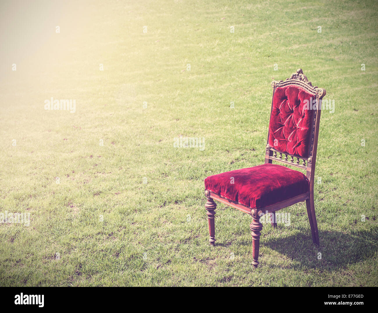 Vintage antique vecchia sedia rossa su erba verde, sfondo astratto. Foto Stock