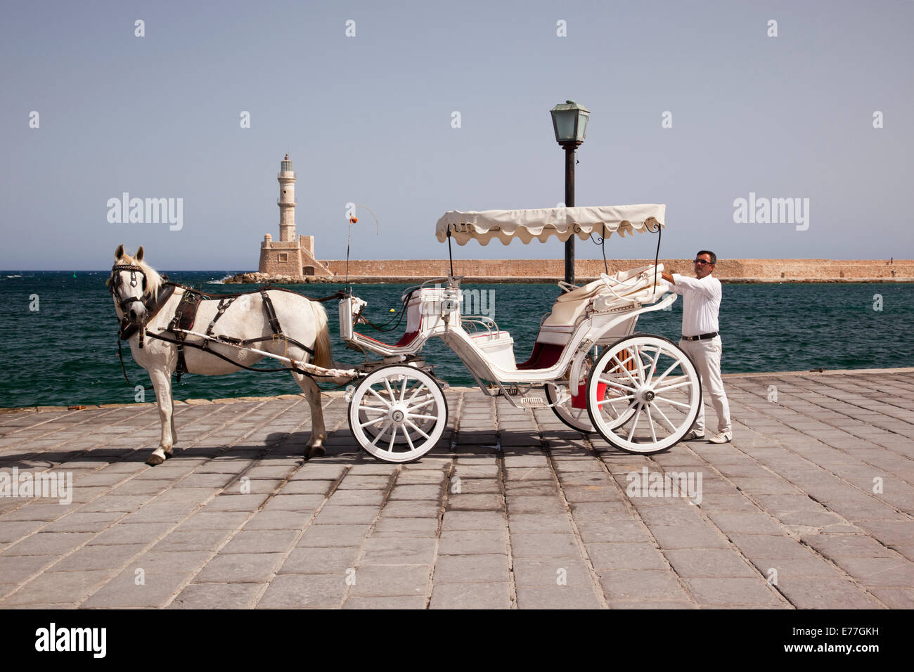 Carrozza tradizionale trainata da cavalli con faro sullo sfondo, Chania Harbour, Creta, Grecia Foto Stock