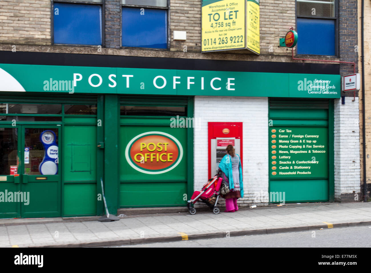 Un donne asiatiche con bambino utilizzando un bancomat ATM presso un ufficio postale in Attercliffe Sheffield South Yorkshire Regno Unito Foto Stock