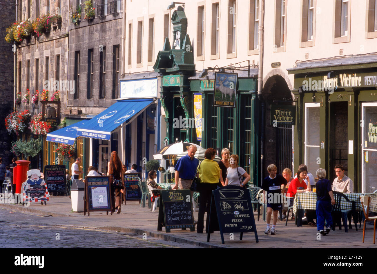 Le persone al marciapiede tavoli presso il vecchio pub lungo il Grassmarket di Edimburgo in Scozia Foto Stock