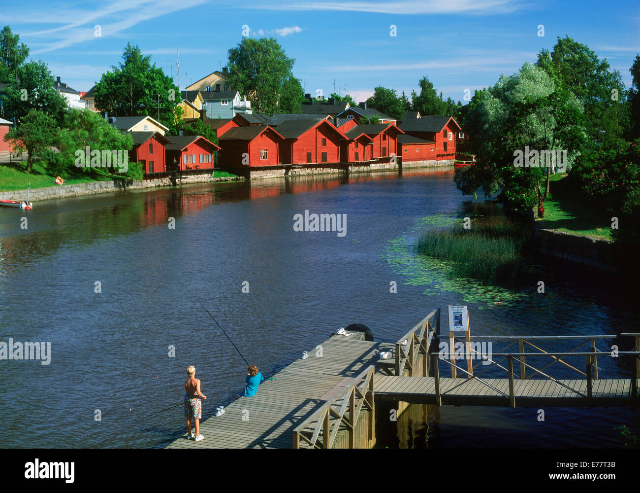 Rosso privato hut residenze e i bambini la pesca lungo le rive del fiume Porvoo in Finlandia Foto Stock