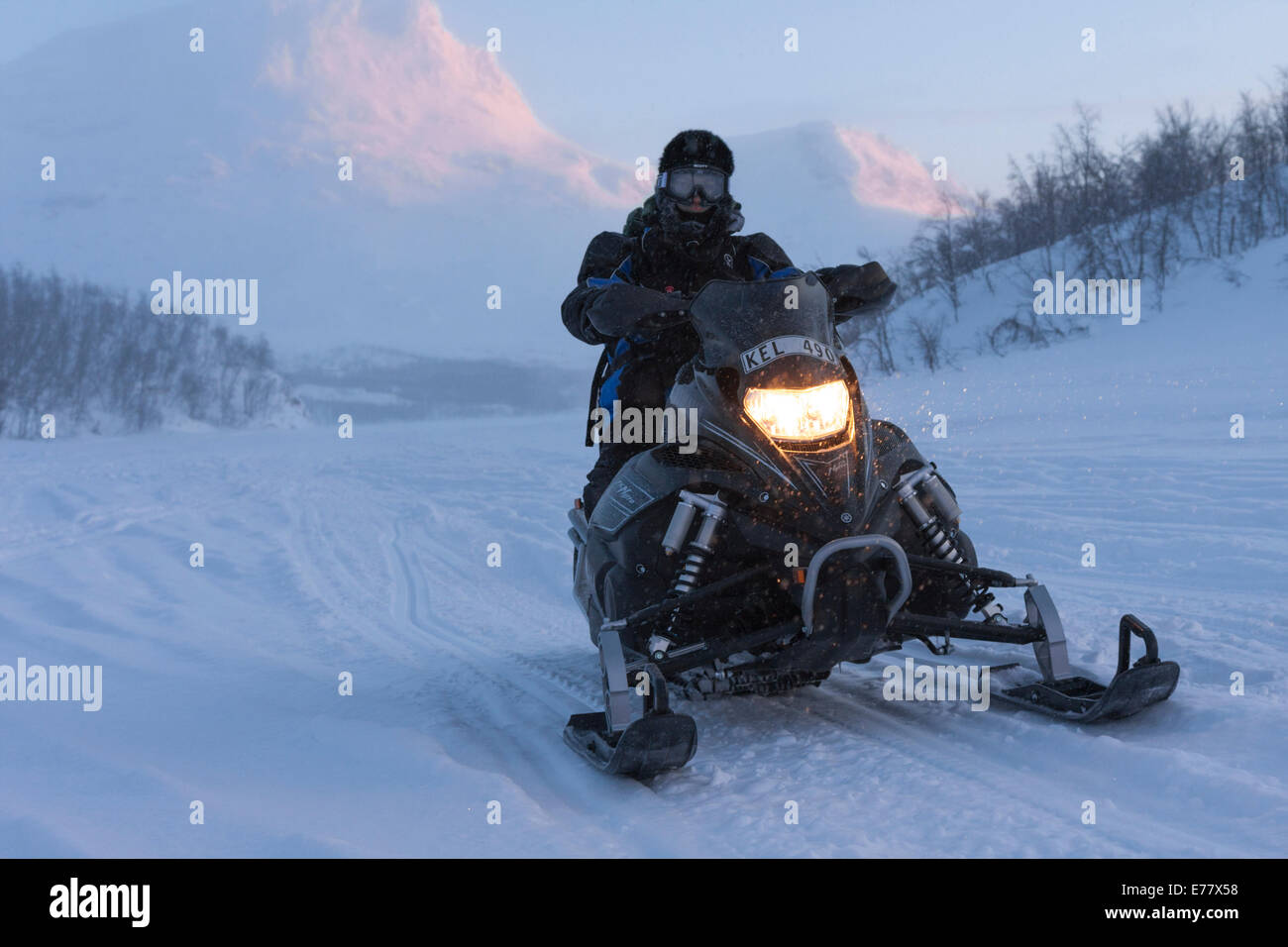 Uomo alla guida di motoslitta in zona di montagna in Lapponia svedese Foto Stock