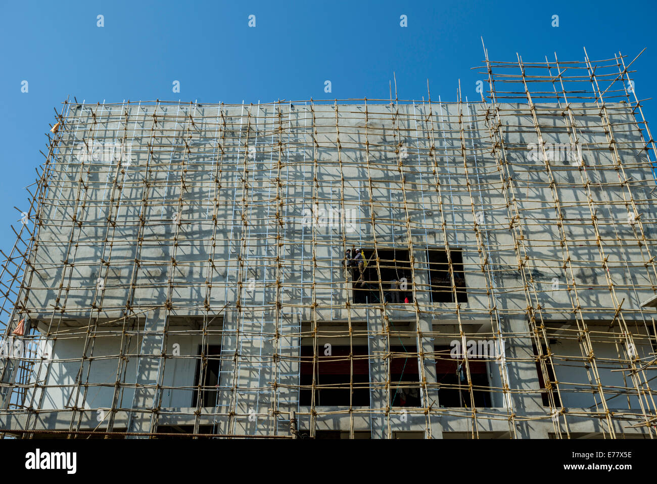 Un sito di costruzione di un nuovo edificio in calcestruzzo con bambù ponteggio attaccato, Ahmedabad, Gujarat, India Foto Stock