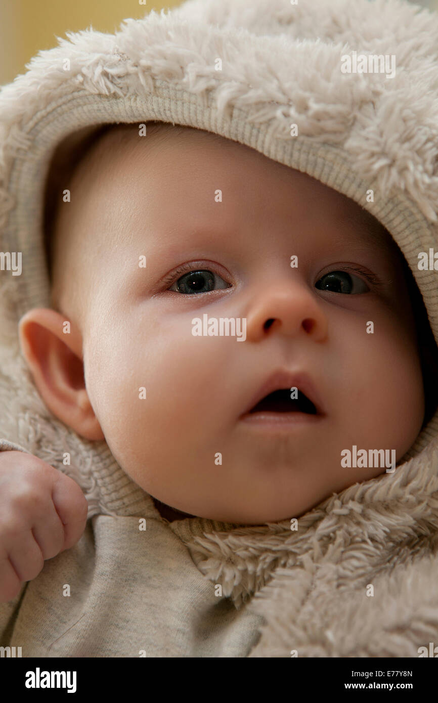 Baby girl, 2 mesi, indossando una pelliccia abito Foto Stock