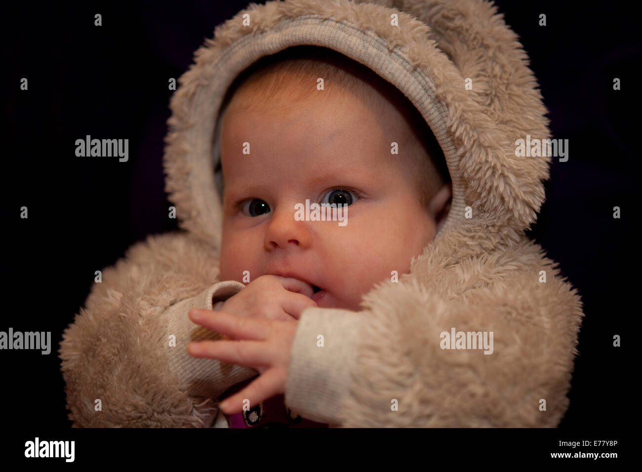 Baby girl, 2 mesi, indossando una pelliccia abito Foto Stock