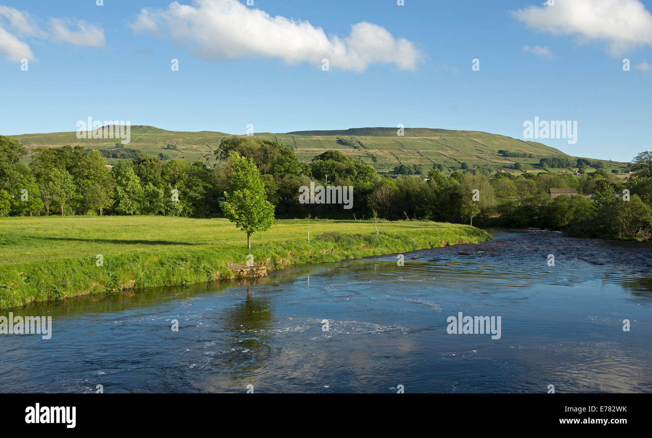 Paesaggio rurale vicino a villaggio inglese di Hawes con campi di smeraldo e fattorie confinanti con acque blu del Fiume Ure e cloaking colline nelle vicinanze Foto Stock