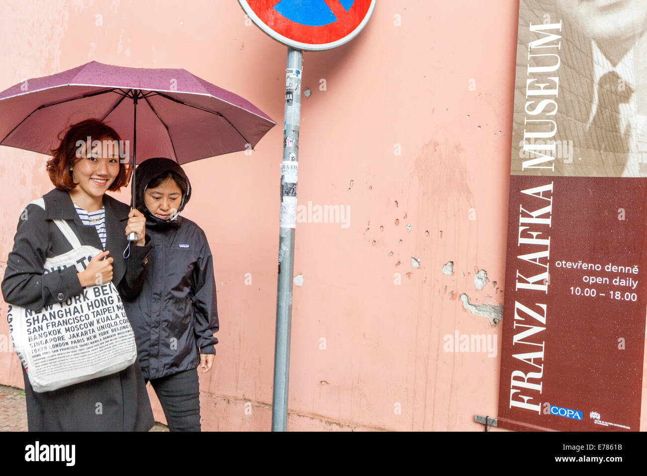 I turisti asiatici passano per strada su Kampa intorno alla pubblicità sul Museo Franz Kafka a Praga Repubblica Ceca Europa giovani donne asiatiche camminano per strada Foto Stock