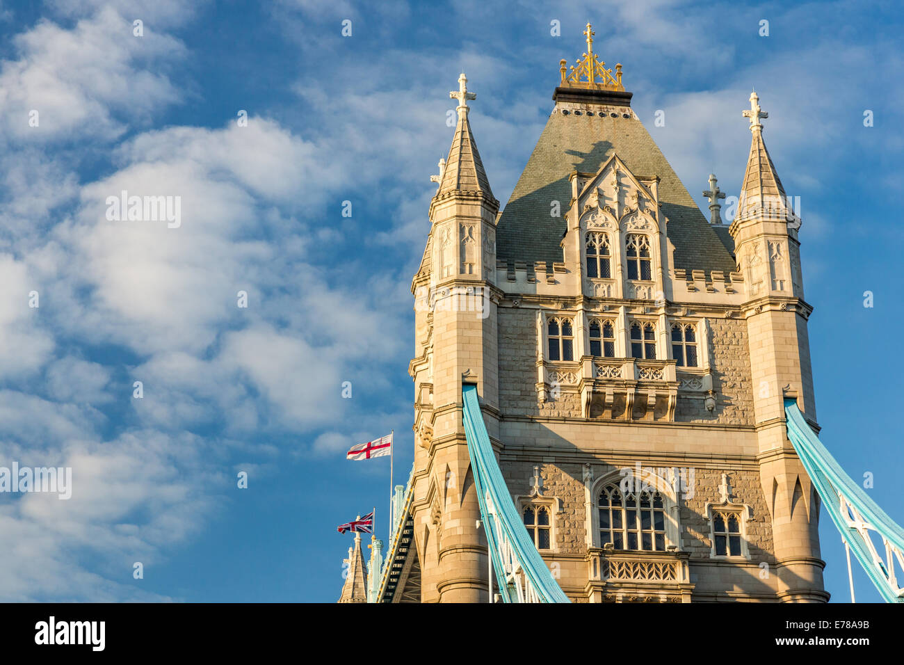 La torre sud del Tower Bridge di Londra, Inghilterra - in golden luce della sera. Bandiere al vento contro il cielo blu Foto Stock