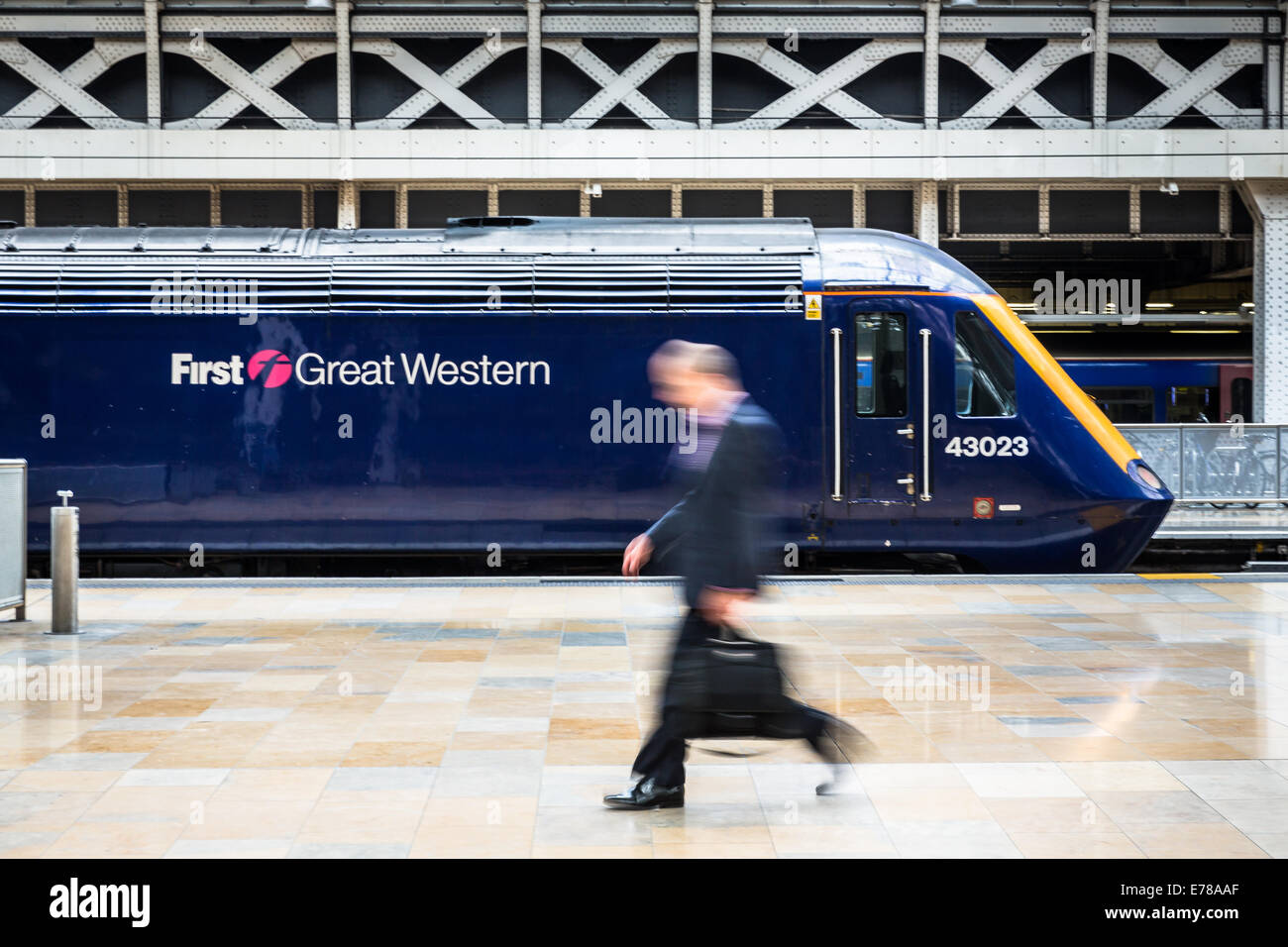 Un business " commuter " passeggiate superato un fermo prima di Great Western treno Intercity alla stazione di Paddington a Londra, Inghilterra, Regno Unito Foto Stock