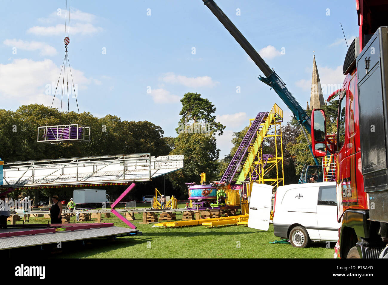 Witney, Oxfordshire, Regno Unito, 9 settembre 2014. Fiera dei lavoratori utilizzare una gru per impostare un rollercoaster ride in blazing sunshine in preparazione per la festa di Witney questo fine settimana. La festa annuale di Santa Maria è stato tenuto dal 1243 per commemorare il re-dedicazione della chiesa di Santa Maria quando il Vescovo ha dato un cervo al rettore di modo che la gente della città potrebbe festeggiare l'occasione. Oggi un arrosto di maiale sulla Chiesa ancora verde segna questa parte della tradizione accanto alle giostre e baracconi, chioschi, musica ed eventi sportivi Credito: Ric Mellis/Alamy Live News Foto Stock