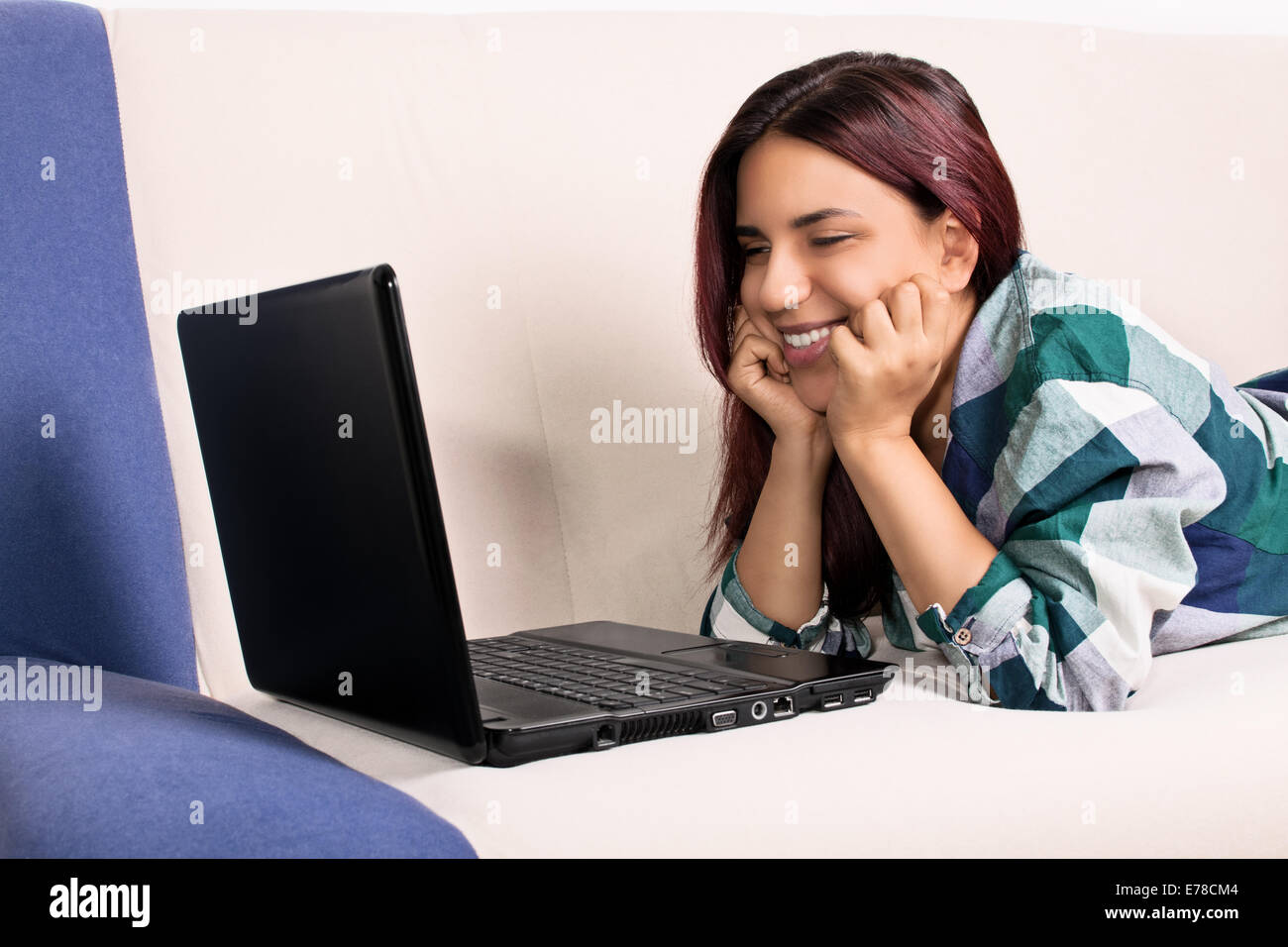Immagine ravvicinata di un bel sorriso ragazza a casa giacente sul suo lettino, guardando una schermata di un laptop. Sono contento quando parlo ai miei amici preferiti. Foto Stock