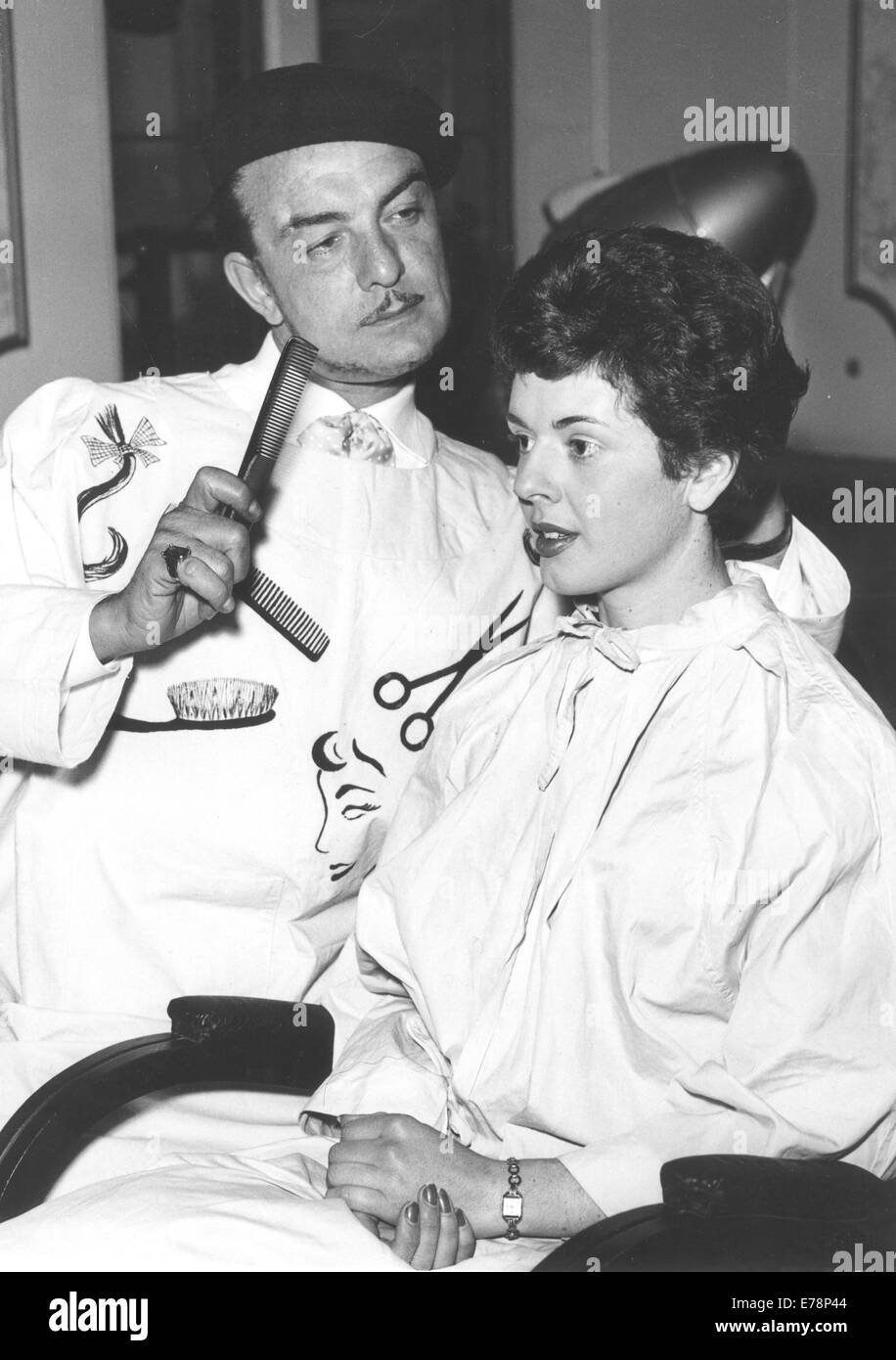 Londra, UK, UK. 3 Mar 1958. Parrucchiere Teazy-Weazy Raymond preparando per l'apertura del Quartiere Latino, indossa il suo costume boemo medicazione mentre i capelli di Deirdre Rossiter presso il suo salone. Molti noti personaggi del mondo dell'arte e intrattenimento stanno prendendo parte al 'Artisti e modelli' apertura del Quartiere Latino, con gli ospiti che indossano costumi bohémien. © Keystone foto/ZUMAPRESS.com/Alamy Live News Foto Stock