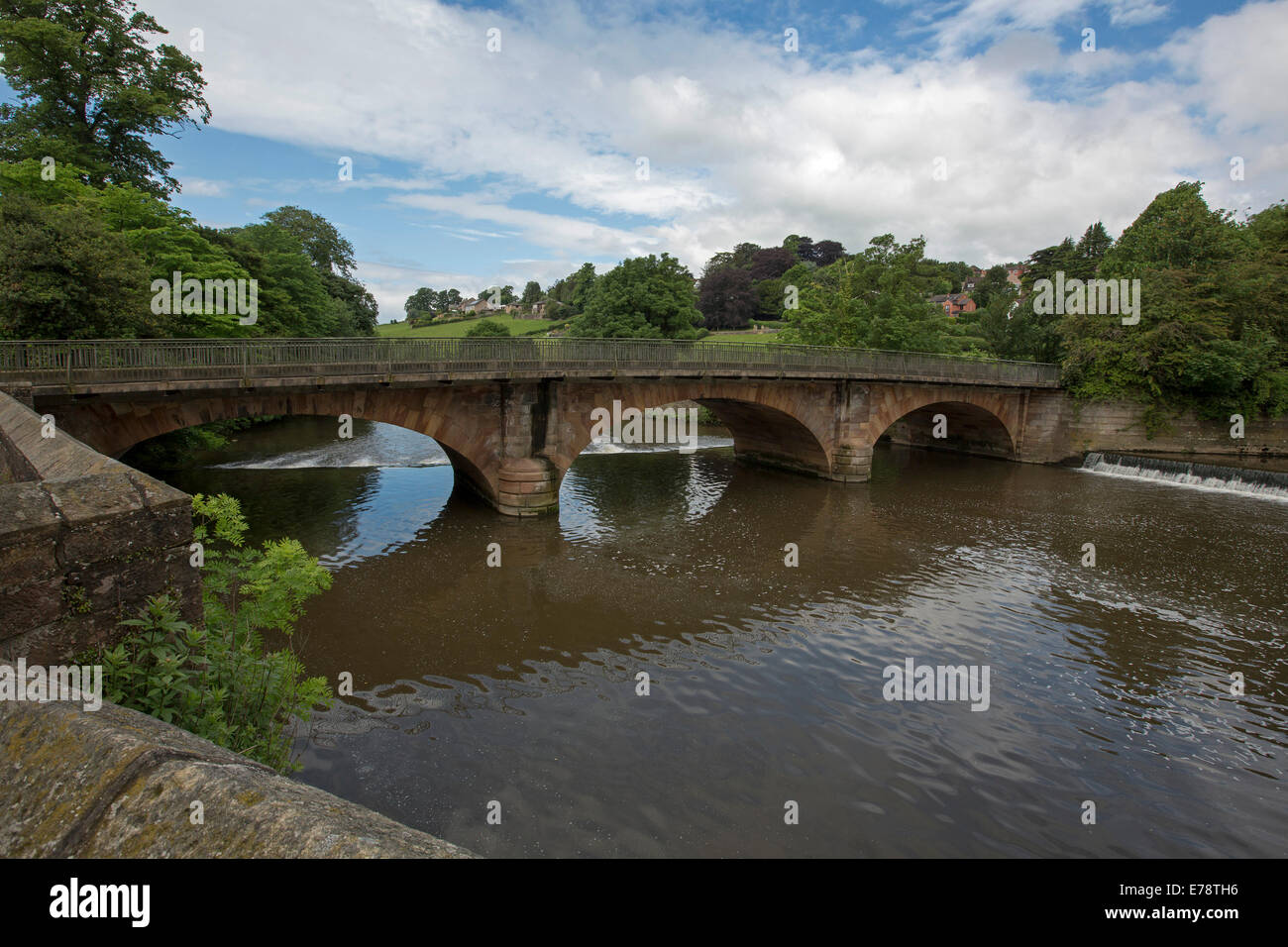 Ornato arcuata di ponte sul fiume Derwent, con ponte, alberi e cielo blu riflessa in acqua calma al villaggio inglese di Belper Foto Stock