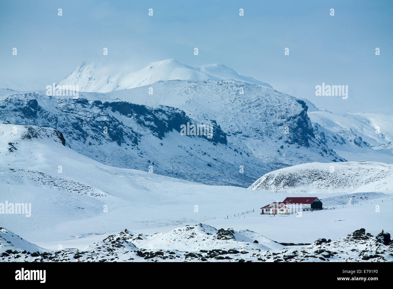 Un agriturismo isolato nella neve con la massa di Katla oltre, sud dell'Islanda Foto Stock