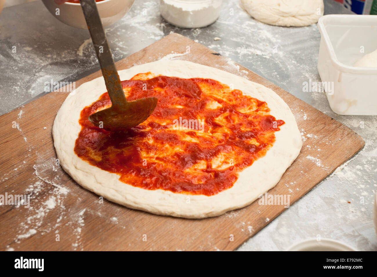 Diffusione di salsa di pomodoro fresco sulla pizza fatta in casa con crosta di pasta acida Foto Stock