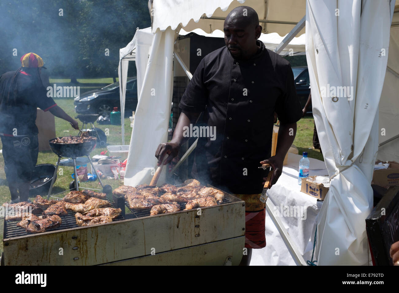 L'uomo la cottura di grandi quantità di carne su un enorme barbecue aperto Foto Stock