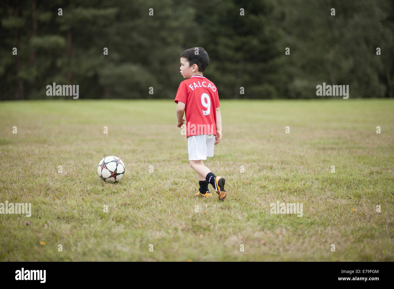 Giovane ragazzo giocando a calcio in una Manchester United kit. Foto Stock