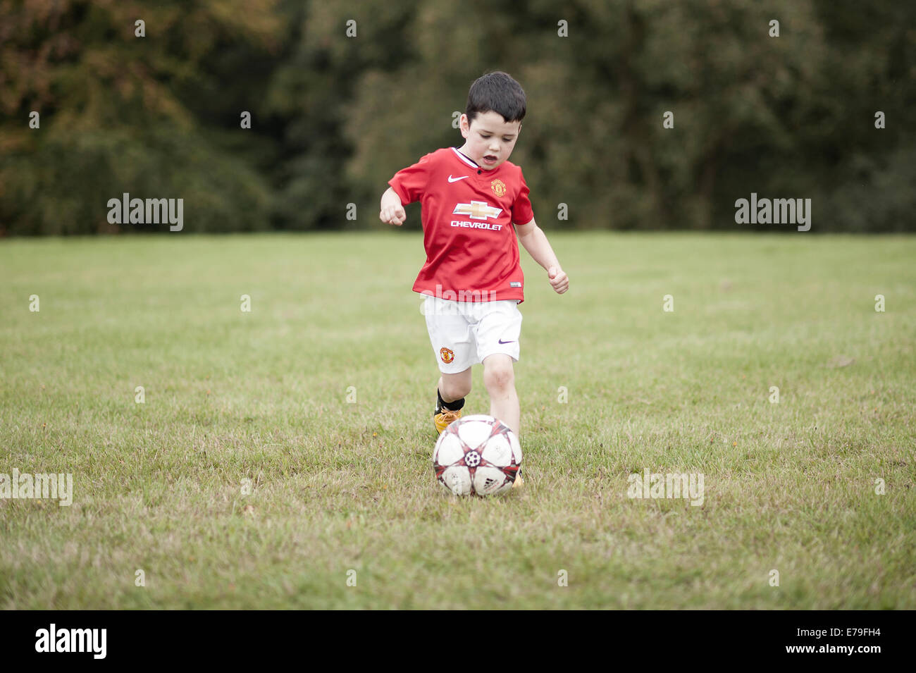 Giovane ragazzo giocando a calcio in una Manchester United kit. Foto Stock