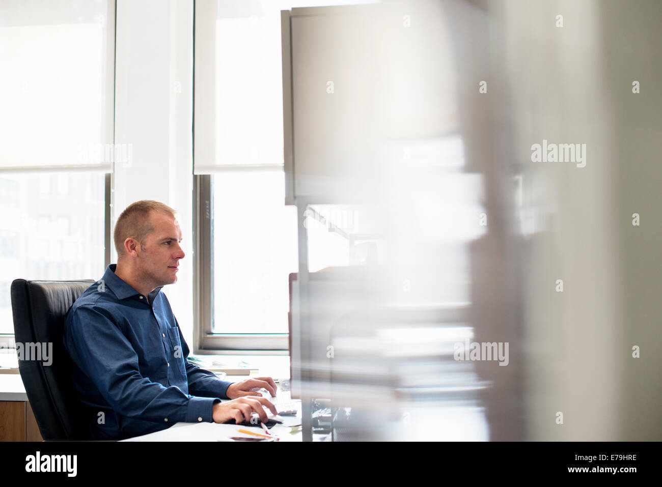 Un uomo che lavora in un ufficio a una scrivania utilizzando un mouse del computer. Incentrato su un'attività. Foto Stock