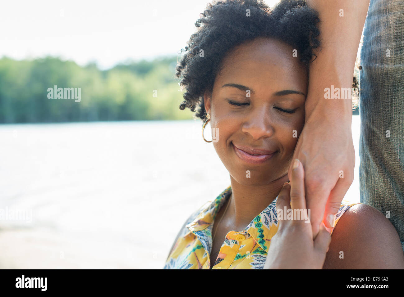 Una donna tenendo la mano di una persona alla sua guancia e sorridente. Foto Stock