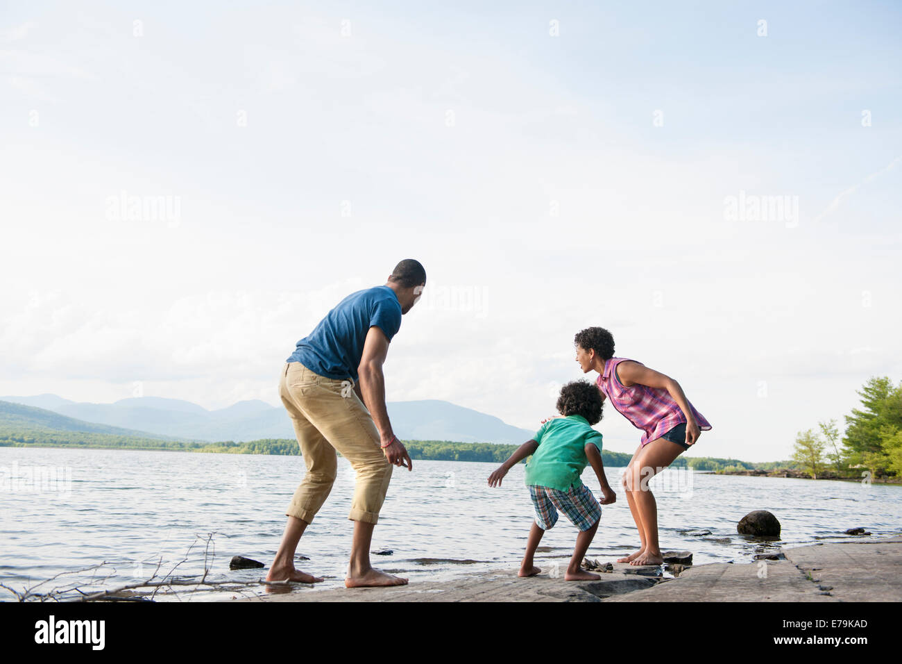 Una famiglia, la madre e il padre e il figlio giocando sulle sponde di un lago. Foto Stock
