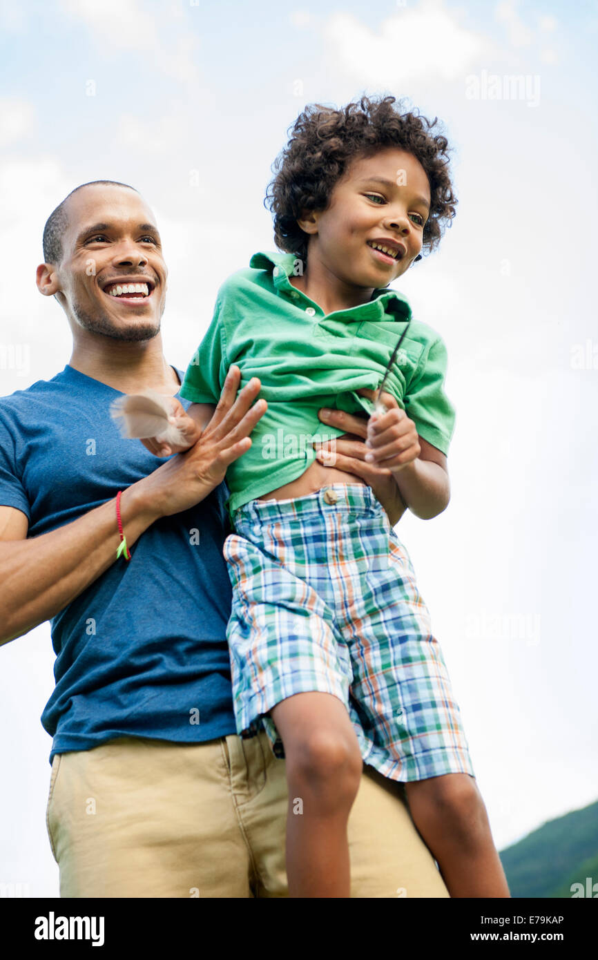 Un uomo sollevando il suo figlio tra le braccia la riproduzione all'esterno. Foto Stock